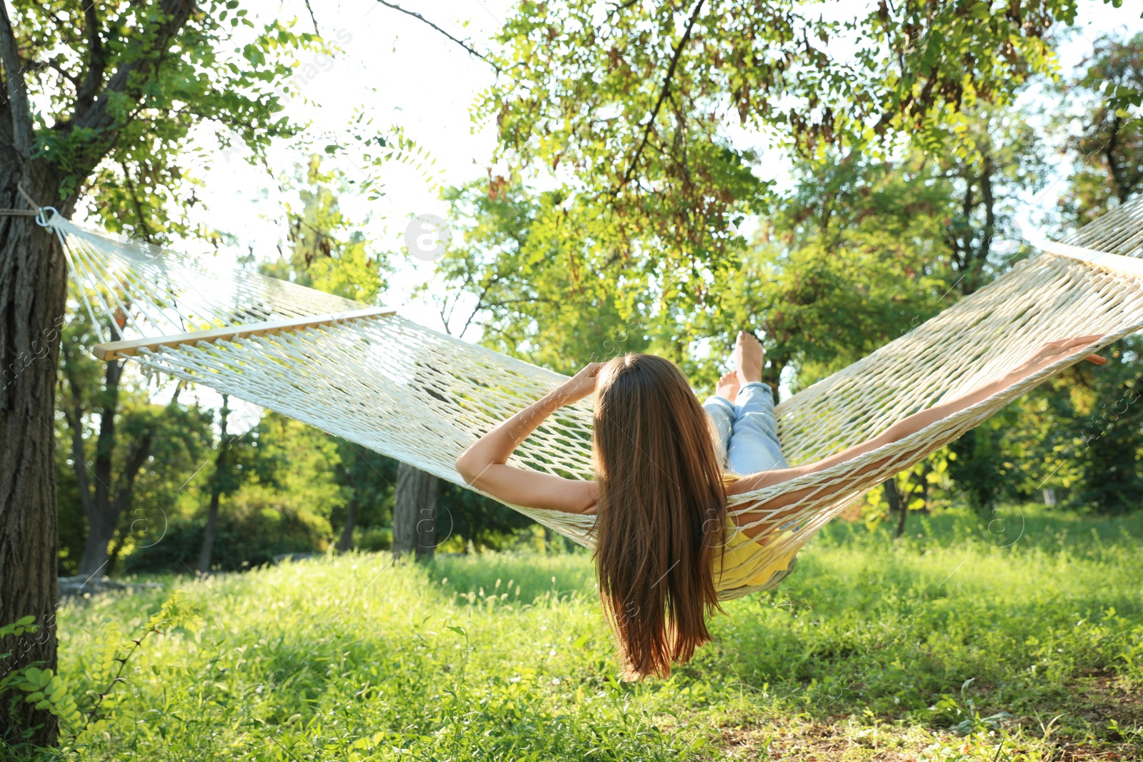 Photo of Young woman resting in comfortable hammock at green garden