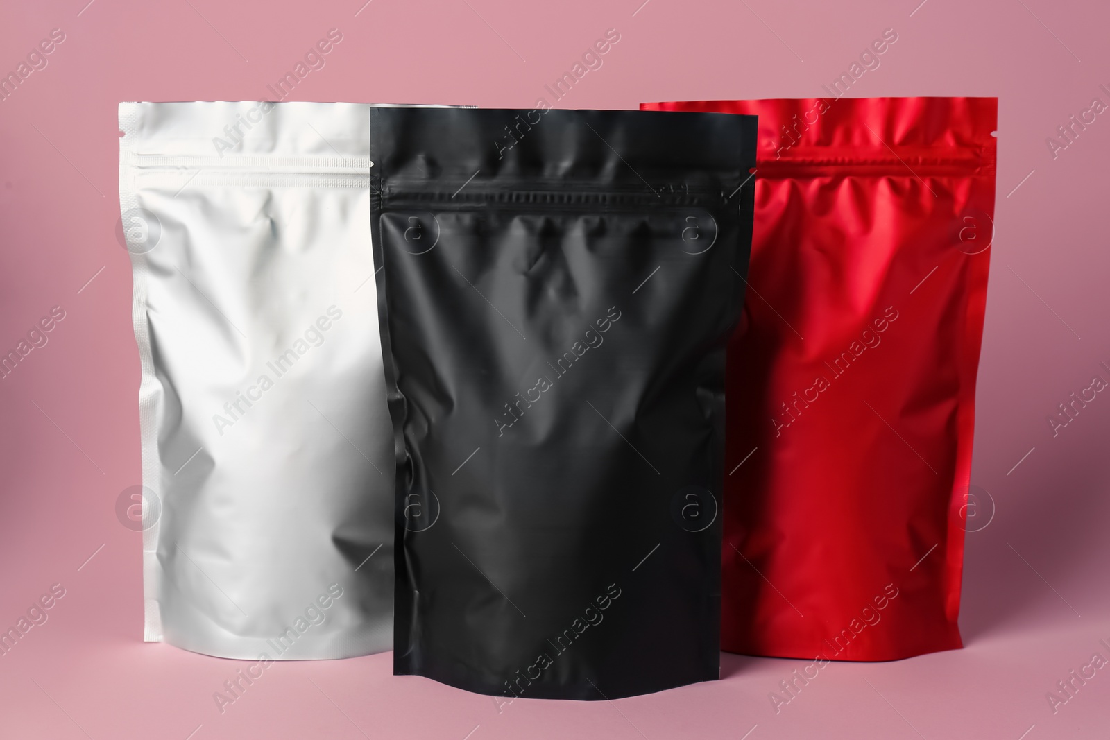 Photo of Different blank foil packages on pink background