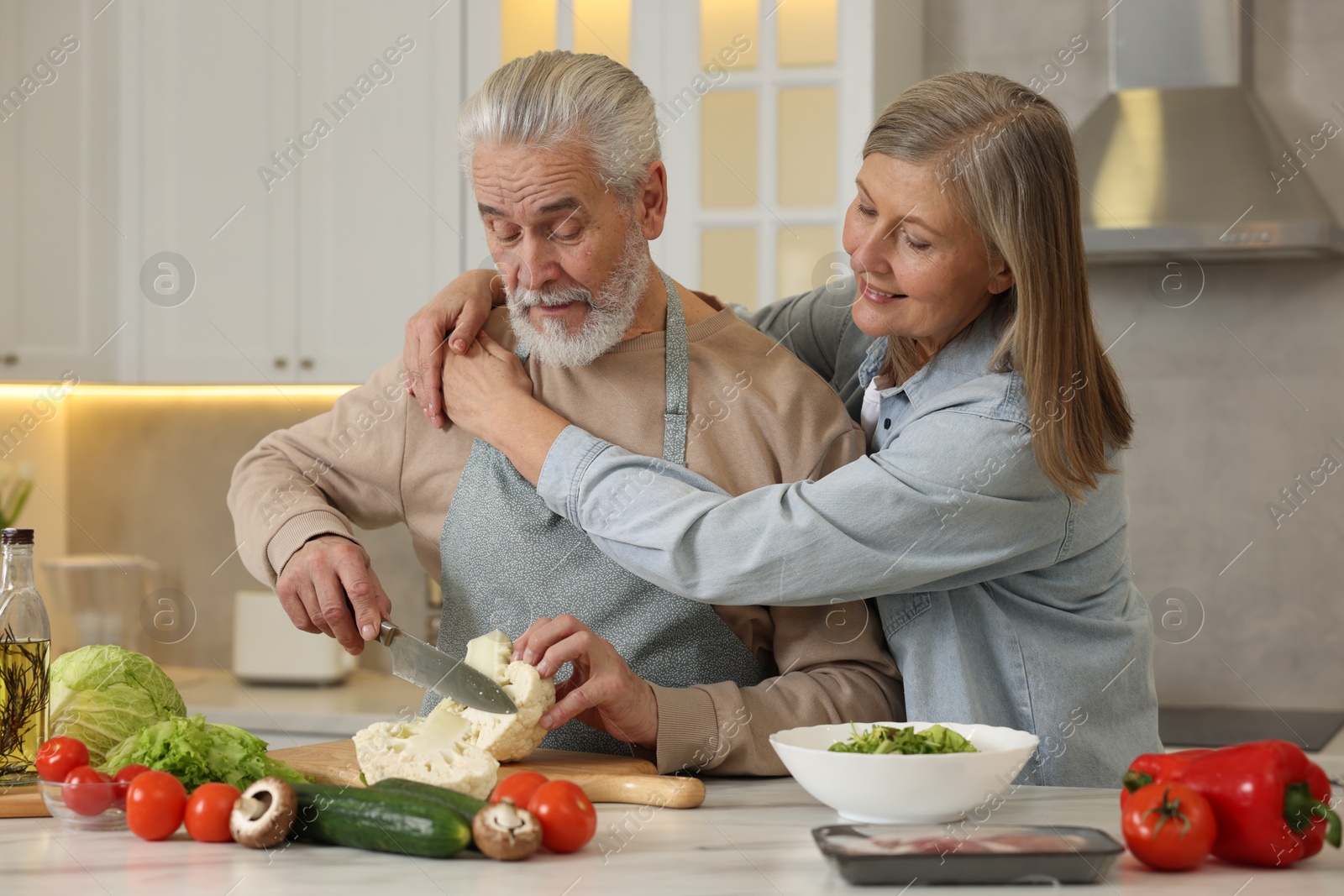 Photo of Happy senior couple cooking together in kitchen