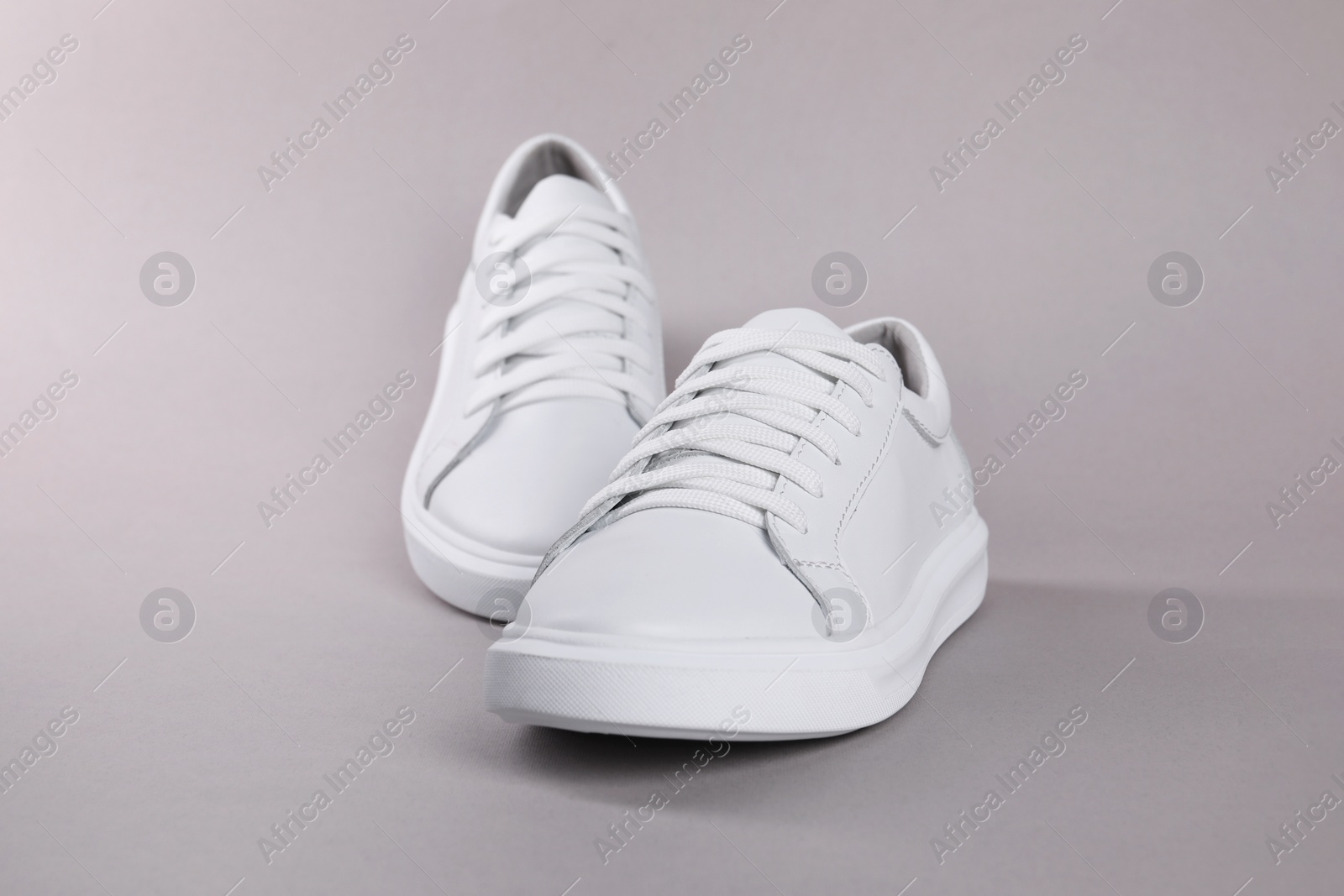 Photo of Pair of stylish white sneakers on grey background