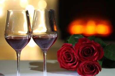Photo of Glasses of wine and flowers on table against blurred lights. Romantic dinner