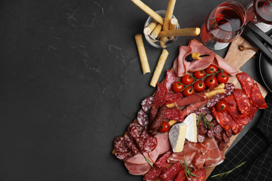 Photo of Tasty ham with other delicacies served on black table, flat lay. Space for text