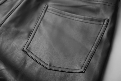 Photo of Black leather trousers with pocket on grey background, closeup