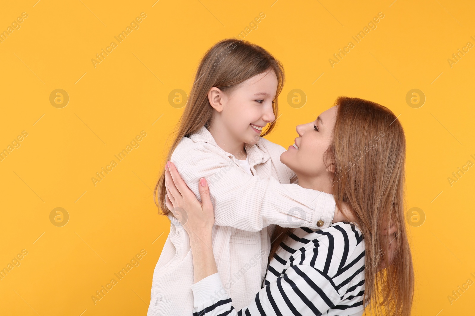 Photo of Portrait of happy mother and her cute daughter on orange background. Space for text