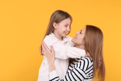 Photo of Portrait of happy mother and her cute daughter on orange background. Space for text