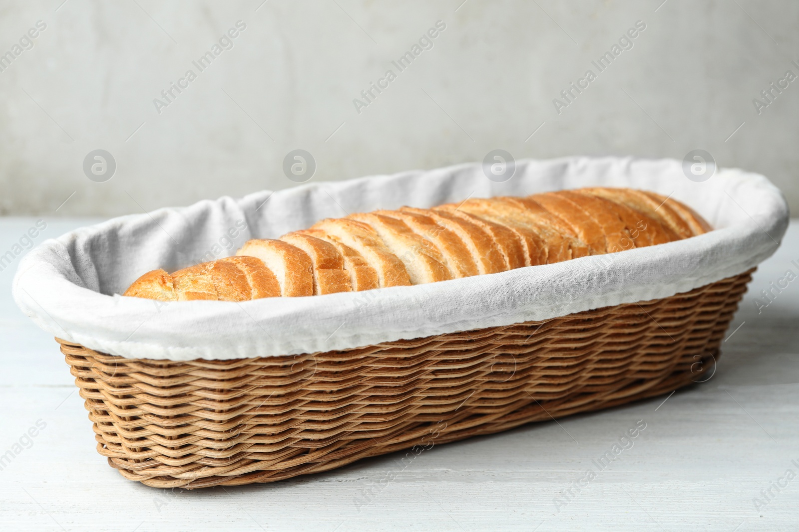 Photo of Slices of bread in basket on white wooden table