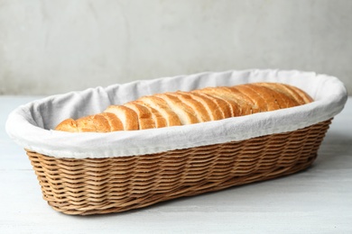 Slices of bread in basket on white wooden table