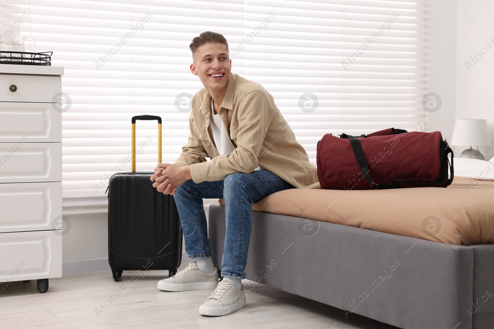 Photo of Smiling guest relaxing on bed in stylish hotel room