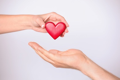 Woman giving red heart to man on white background, closeup. Donation concept