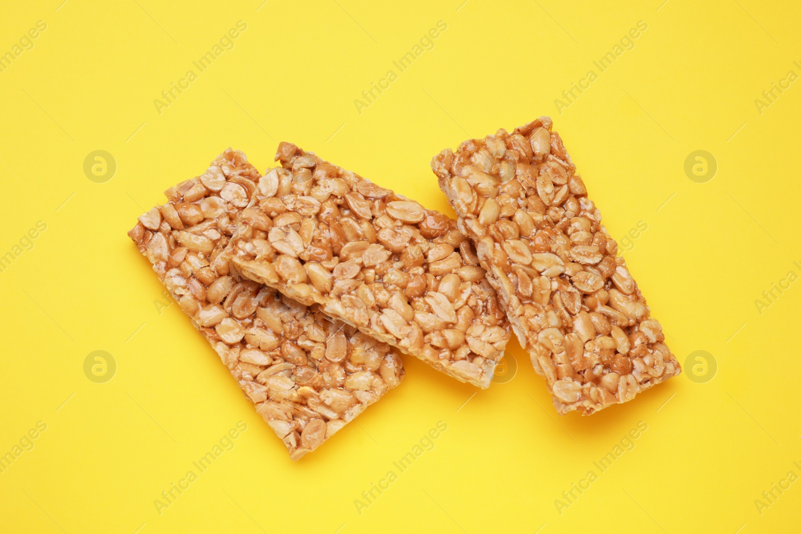 Photo of Tasty peanut bars (kozinaki) on yellow background, flat lay