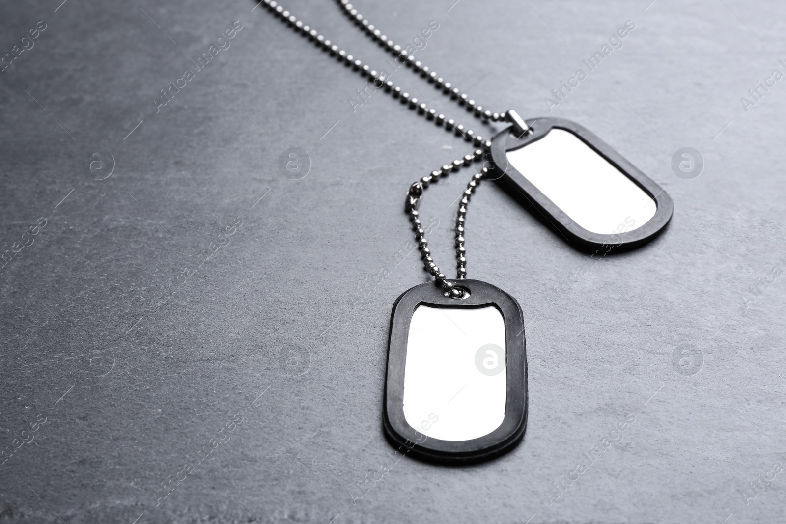 Photo of Blank military ID tags on grey stone surface, space for text