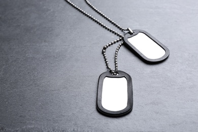 Photo of Blank military ID tags on grey stone surface, space for text