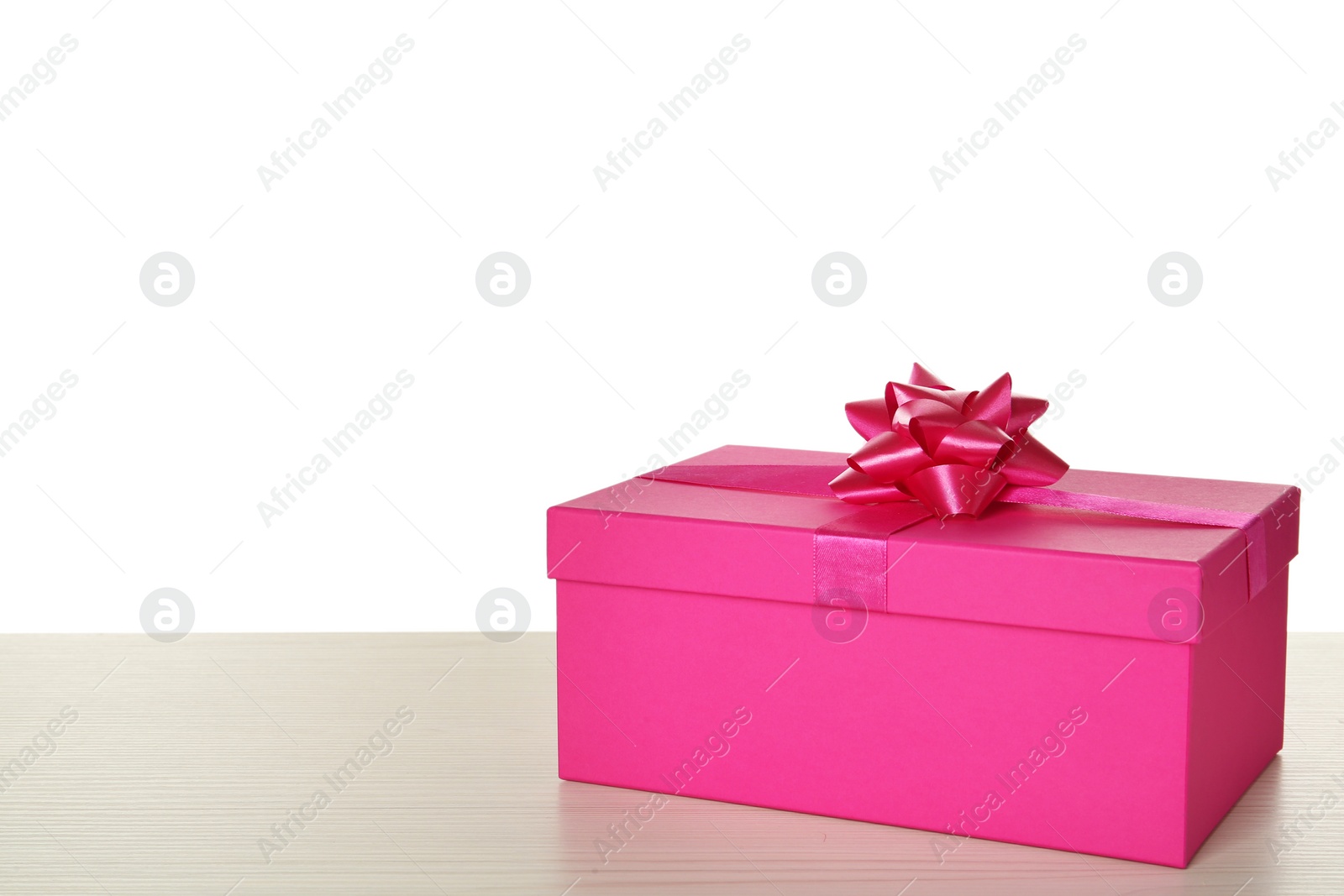 Photo of Pink gift box with bow on wooden table against white background, space for text