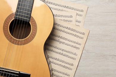 Composition with guitar and music notations on light wooden table, flat lay
