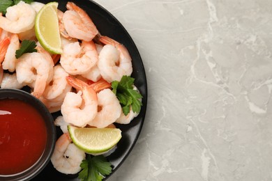 Photo of Tasty boiled shrimps with cocktail sauce, parsley and lime on light grey table, top view. Space for text