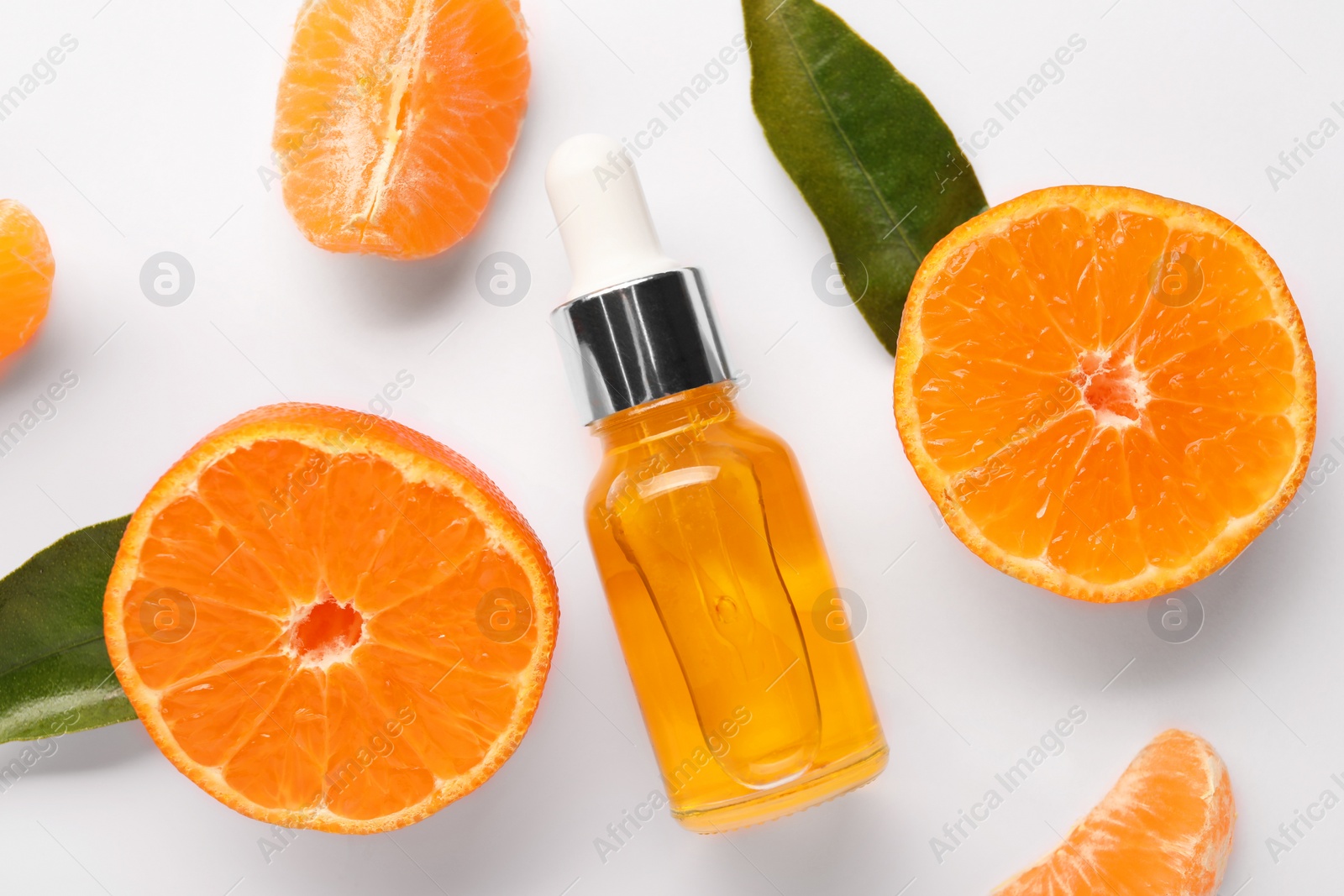 Photo of Aromatic tangerine essential oil in bottle, leaves and citrus fruits on white table, flat lay