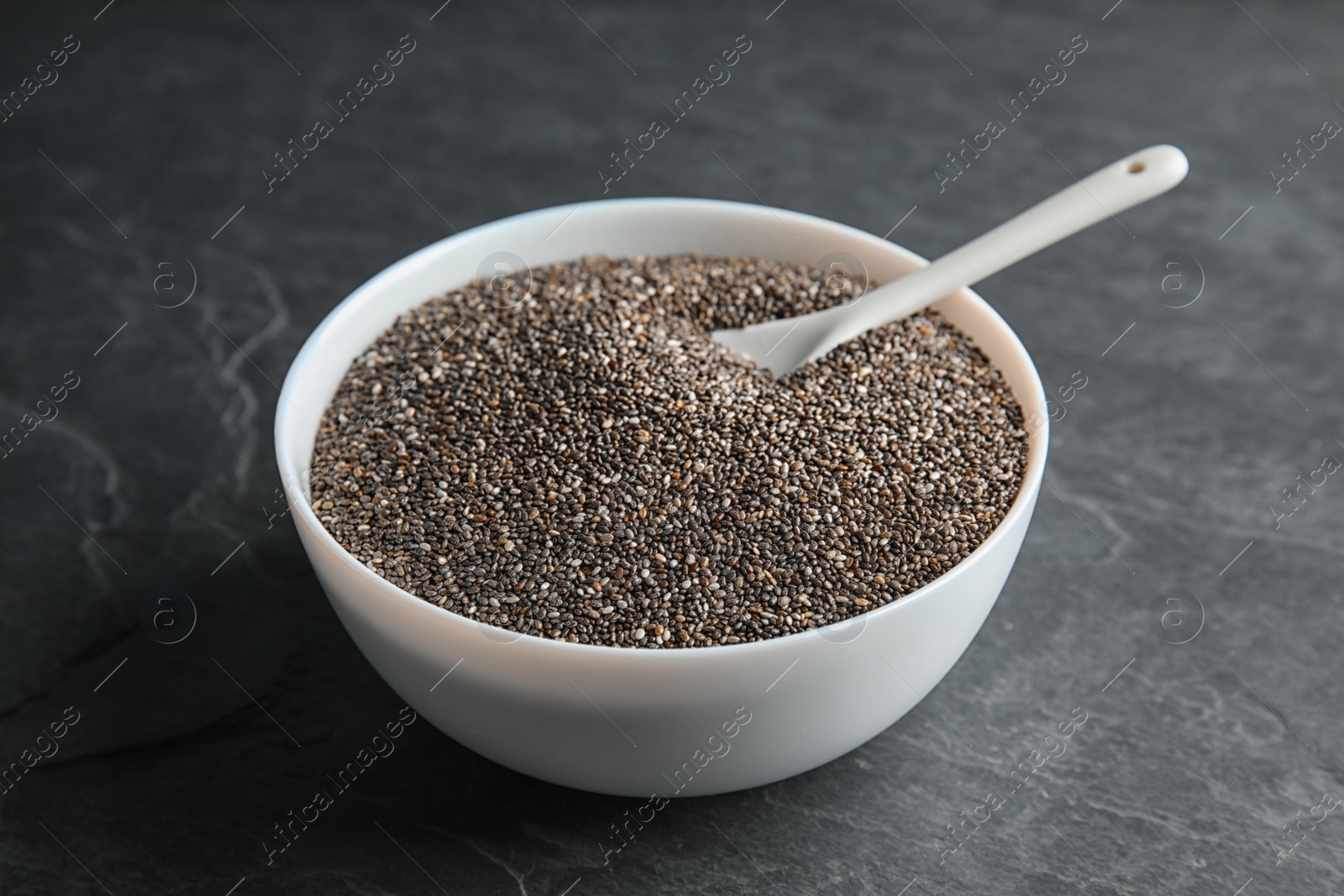 Photo of Bowl and spoon with chia seeds on grey background