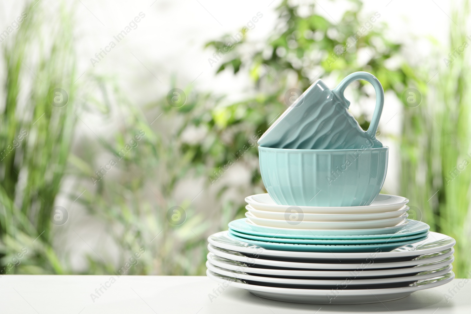 Photo of Beautiful ceramic dishware and cup on white table outdoors, space for text