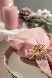 Photo of Pink fabric napkin with beautiful decorative ring for table setting on plate, closeup