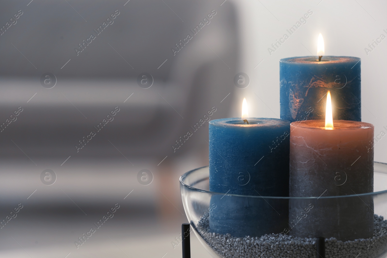 Photo of Bowl with burning candles on blurred background. Space for text
