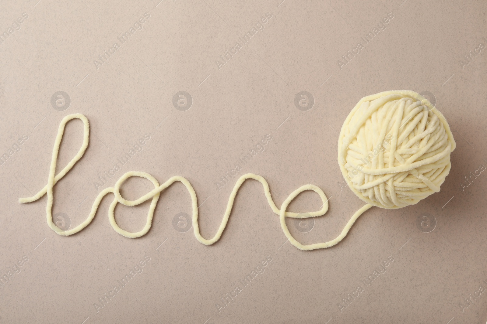 Photo of Word Love made of woolen yarn on grey background, top view