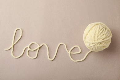 Photo of Word Love made of woolen yarn on grey background, top view