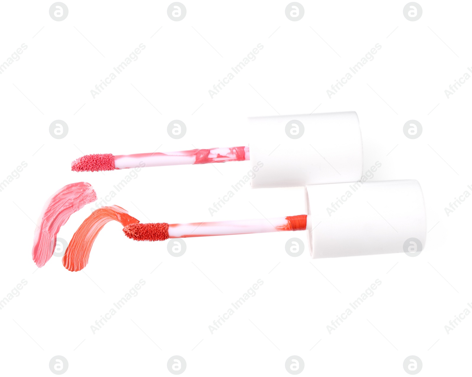 Photo of Strokes of color lip glosses and applicators isolated on white