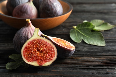 Fresh ripe figs with leaves on wooden table. Tropical fruit