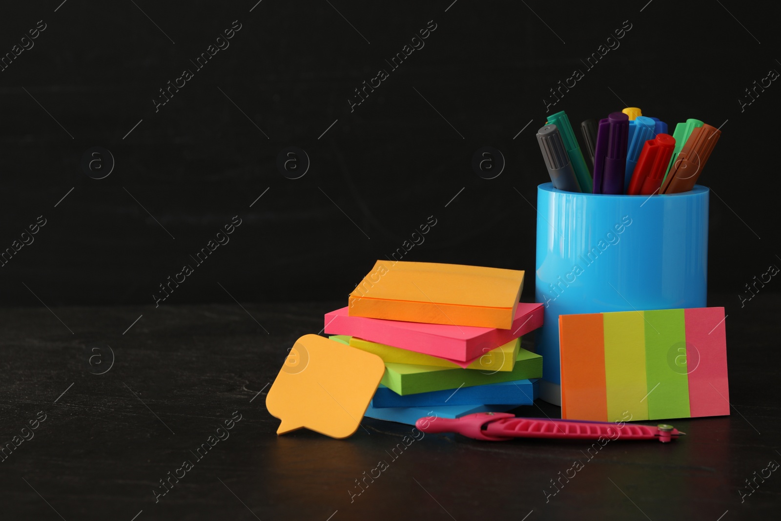Photo of Different school stationery on stone table near blackboard, space for text. Back to school