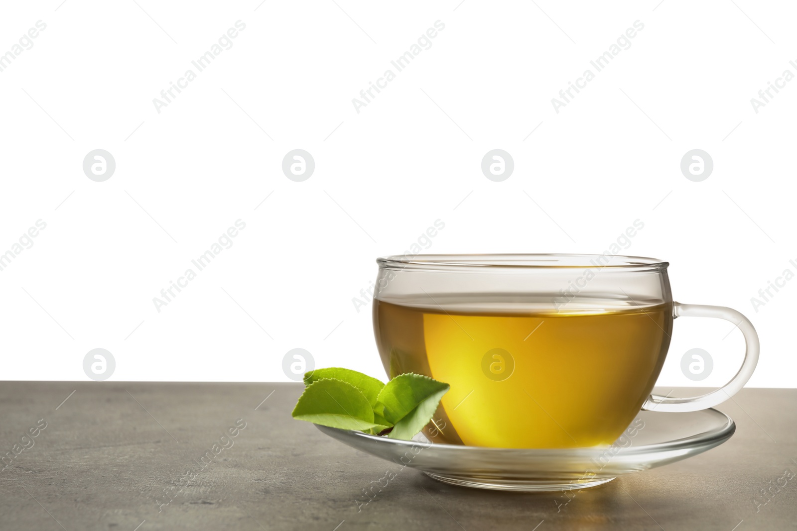 Photo of Cup of green tea and leaves on grey table