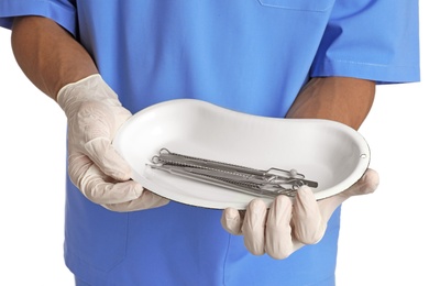 Male doctor holding dish with medical tools on white background, closeup. Medical objects