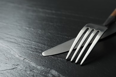 Photo of Stylish cutlery on black table, closeup. Space for text