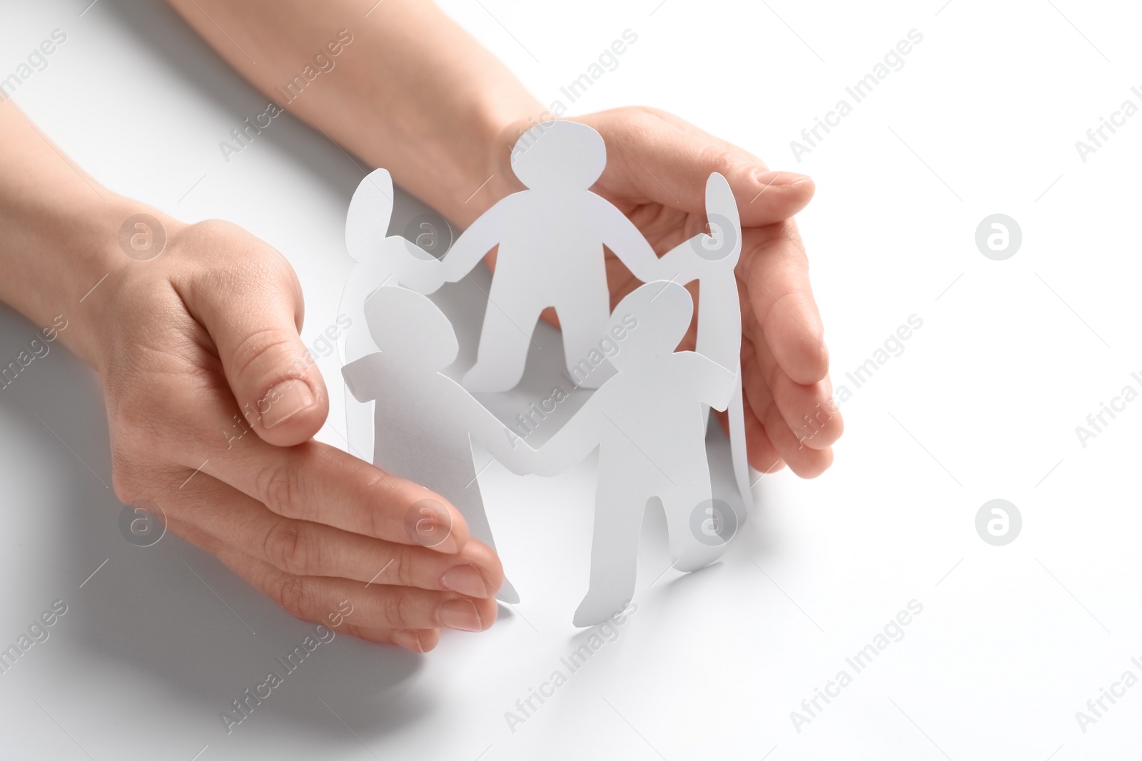 Photo of Young woman protecting paper people on light background. Unity concept