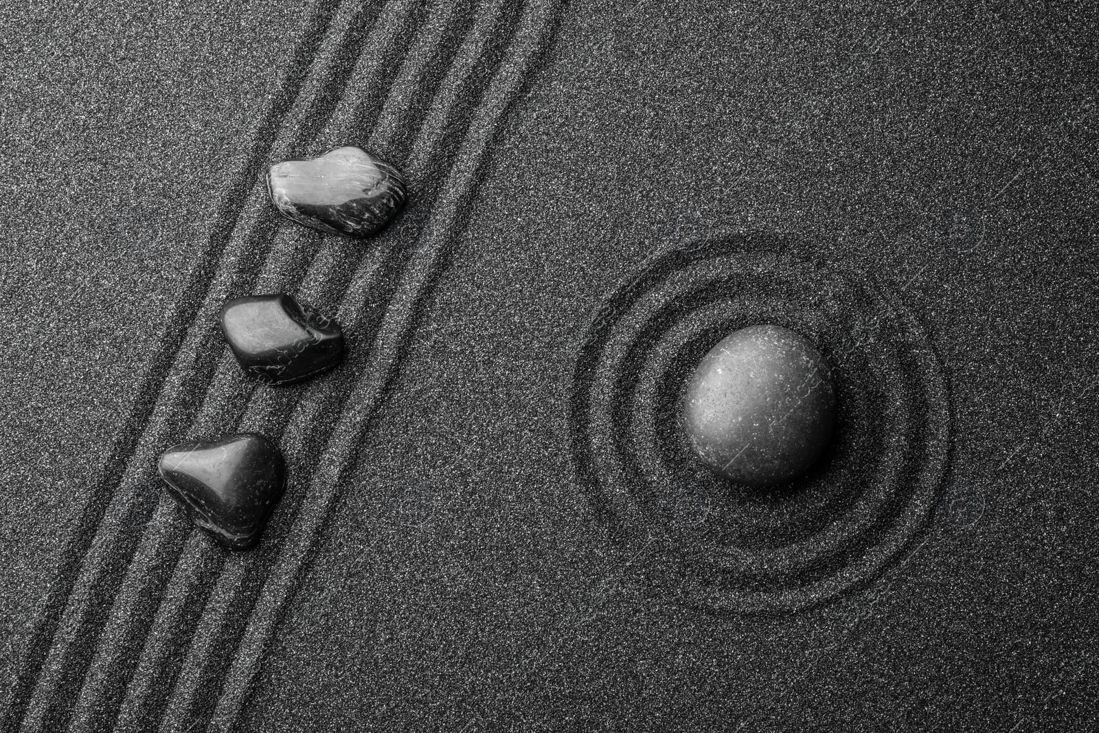 Photo of Black sand with stones and beautiful pattern, flat lay. Zen concept