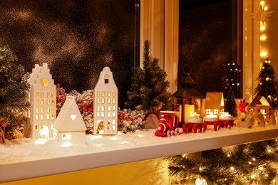 Photo of House shaped lanterns and Christmas decor on windowsill indoors