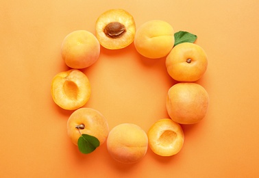 Photo of Delicious ripe sweet apricots on orange background, flat lay. Space for text