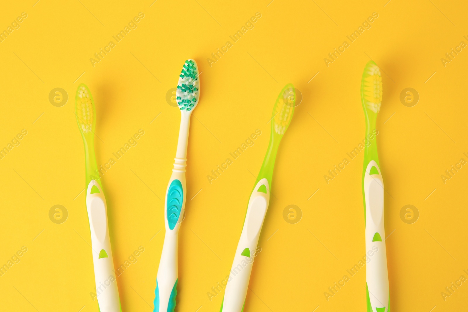 Photo of New toothbrushes on yellow background, flat lay