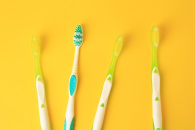 New toothbrushes on yellow background, flat lay