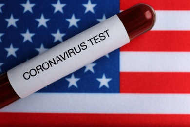 Test tube with blood sample on American flag, top view. Coronavirus pandemic in USA