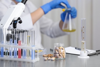 Pistachios on table and scientist proceeding quality control in laboratory