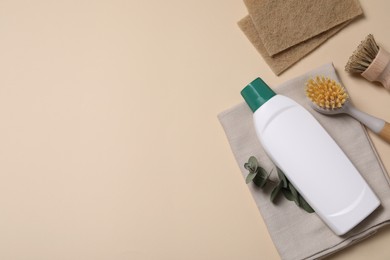 Photo of Bottle of cleaning product, sponges and brushes on beige background, flat lay. Space for text