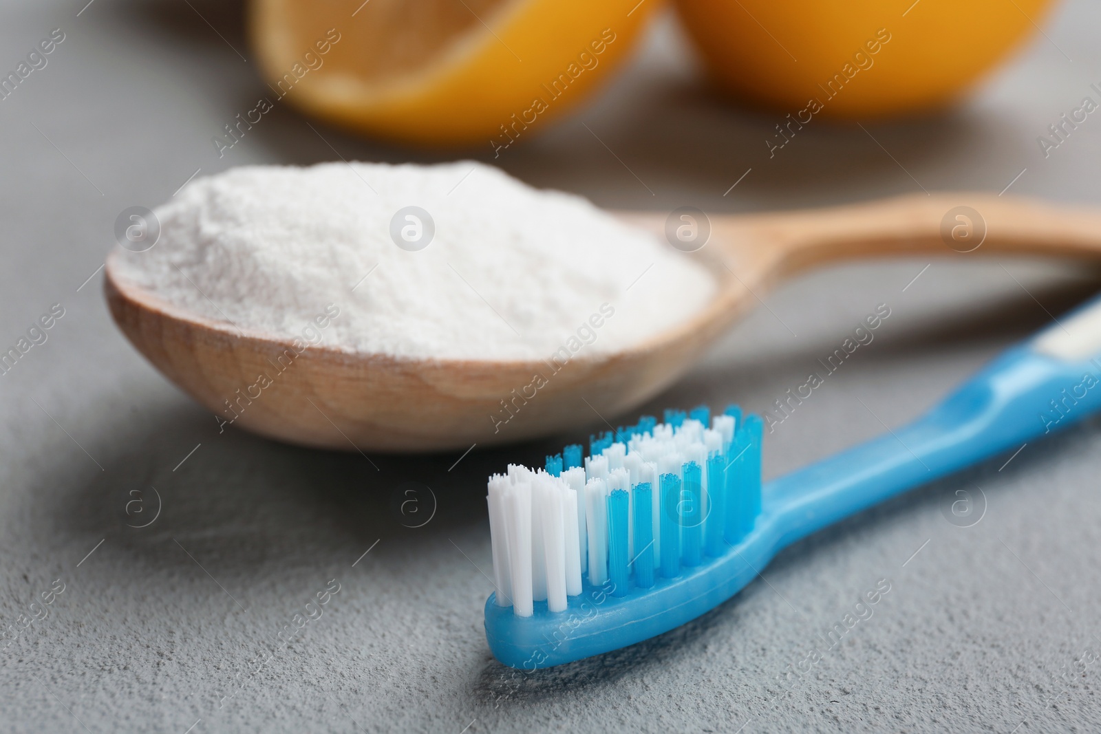 Photo of Spoon with baking soda and toothbrush on gray table