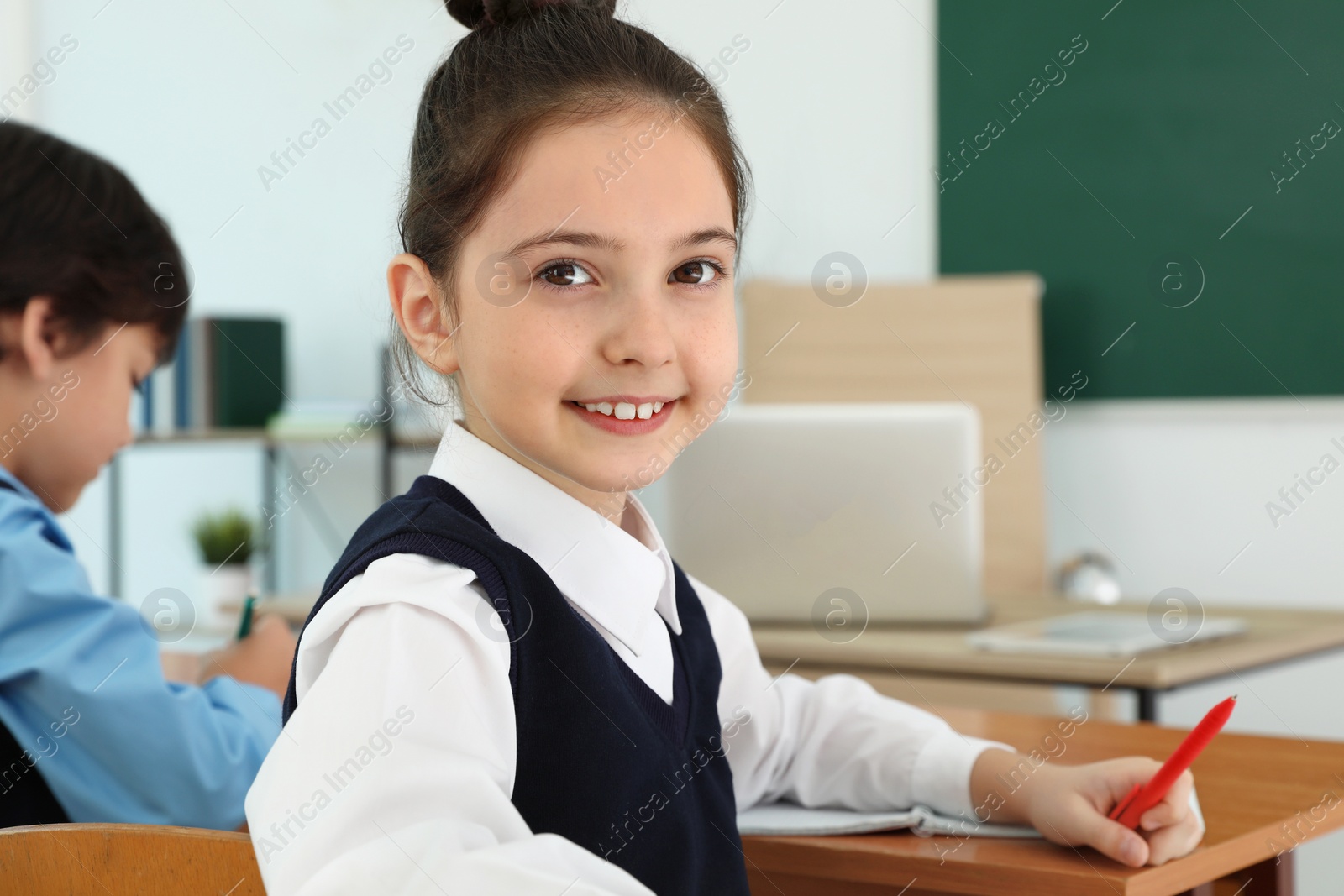 Photo of Girl wearing new school uniform in classroom