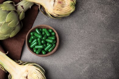 Bowl with pills and fresh artichokes on brown table, flat lay. Space for text