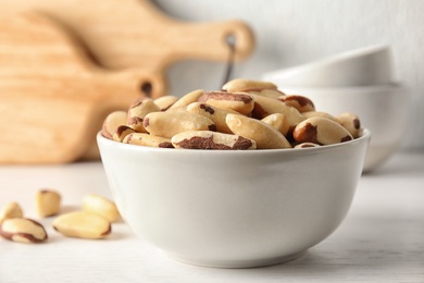 Photo of Bowl with tasty Brazil nuts on white table