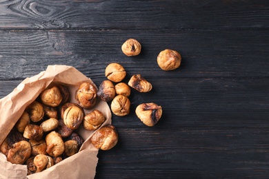Paper bag with dried figs on wooden background, top view. Space for text