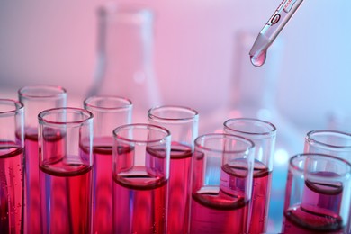 Photo of Dripping reagent into test tube with red liquid, closeup. Laboratory analysis