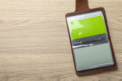 Photo of Leather business card holder with blank cards on wooden table, top view. Space for text