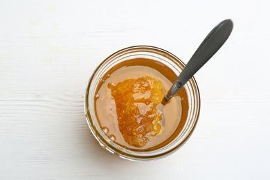 Tasty honey with comb on white wooden table, top view