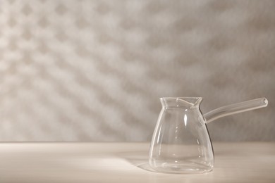 Photo of Empty glass turkish coffee pot on white wooden table. Space for text